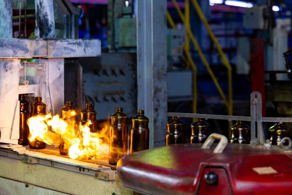 Amber glass bottles passing through a production flame treatment